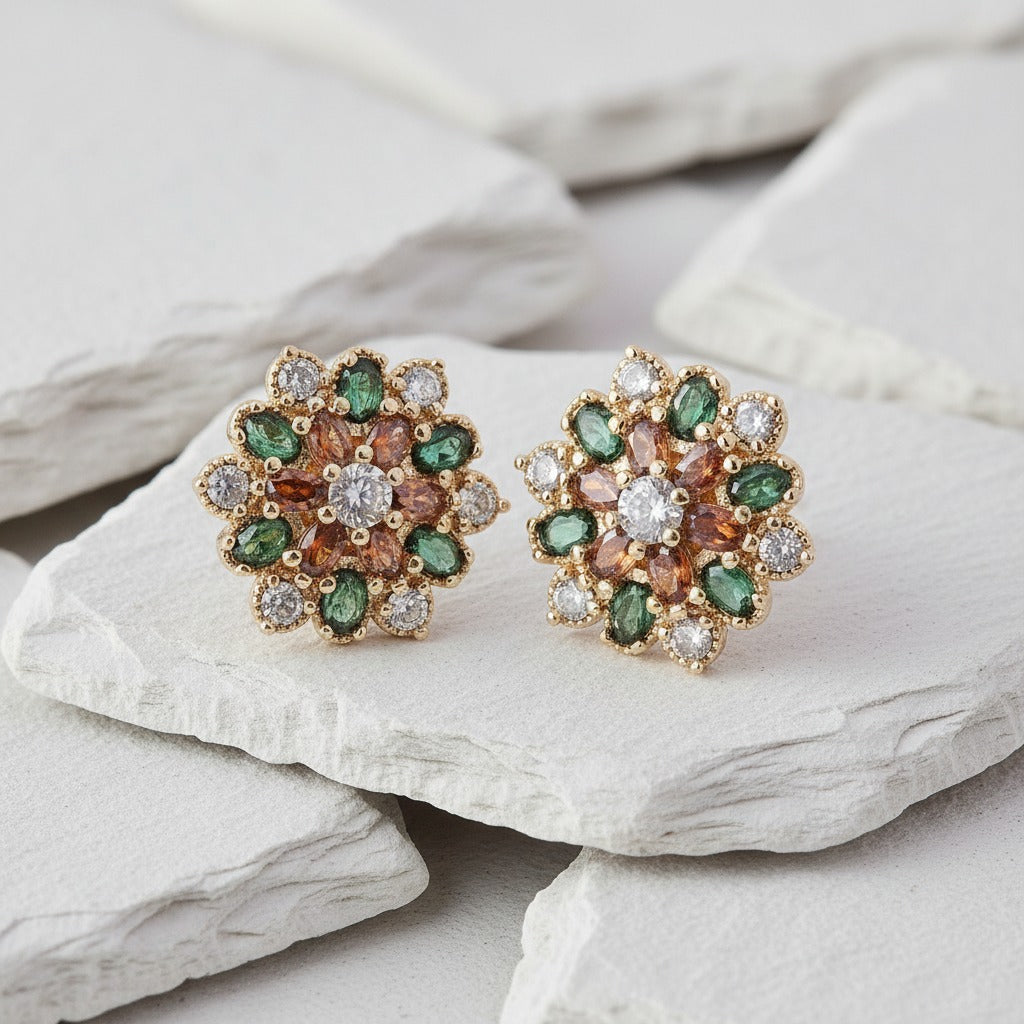 Pair of floral earrings with green and brown gemstones on a stone surface