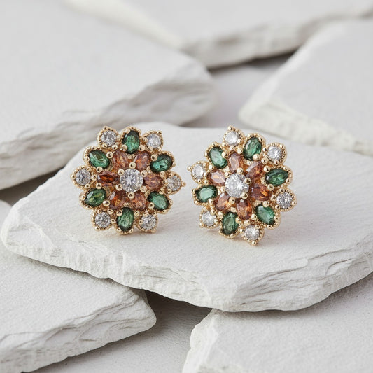 Pair of floral earrings with green and brown gemstones on a stone surface