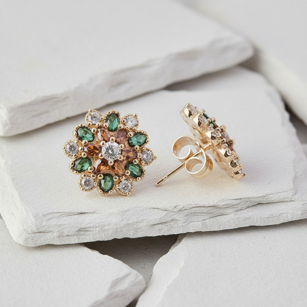 Gold earrings with gemstones on a light stone surface