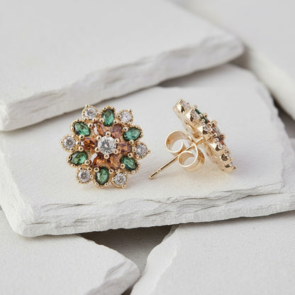 Gold earrings with gemstones on a light stone surface