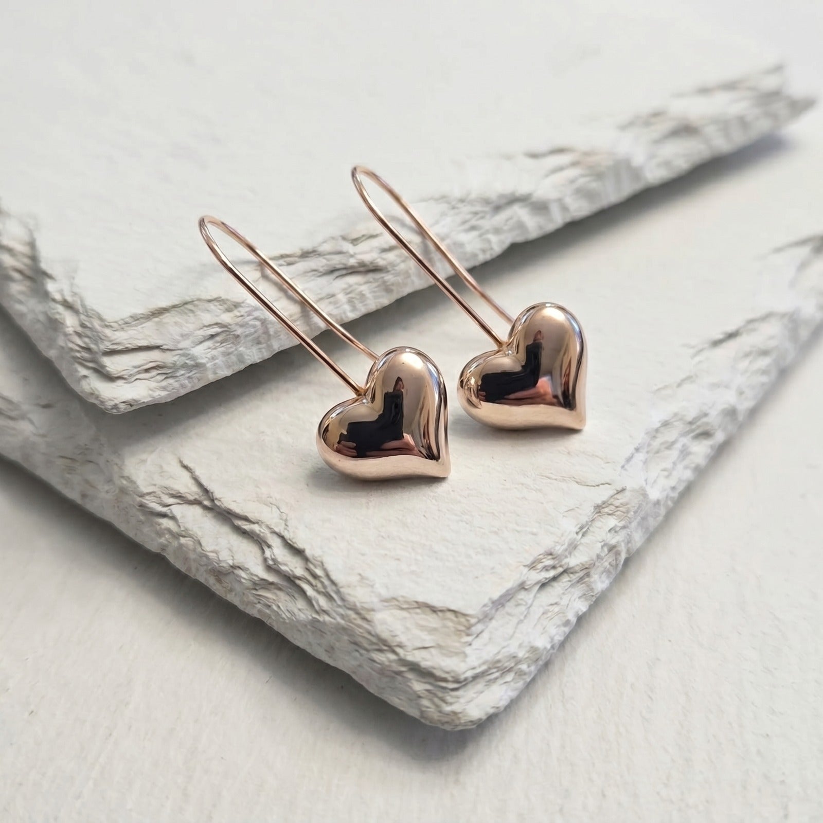 Rose gold heart-shaped earrings on a marble surface 
Small Rose Gold Mini Heart Drop Earrings premium stainless steel waterproof, tarnish-proof, hypoallergenic, and lightweight—perfect for sensitive ears and everyday wear.