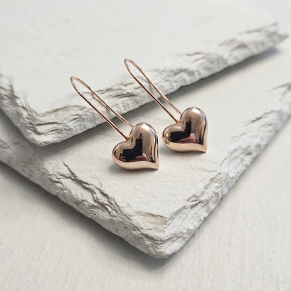 Rose gold heart-shaped earrings on a marble surface 
Small Rose Gold Mini Heart Drop Earrings premium stainless steel waterproof, tarnish-proof, hypoallergenic, and lightweight—perfect for sensitive ears and everyday wear.