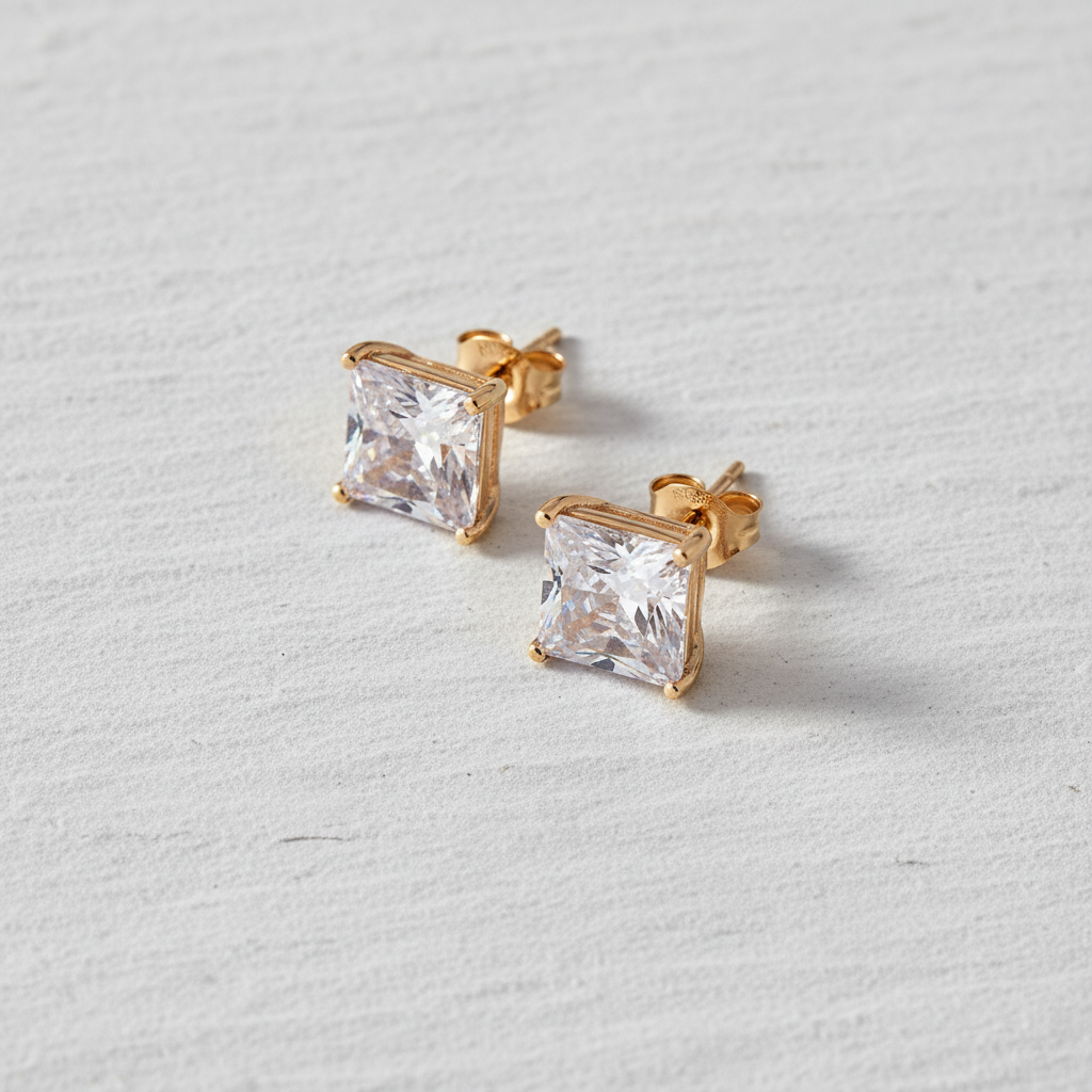 Gold square-cut stud earrings on a light gray background