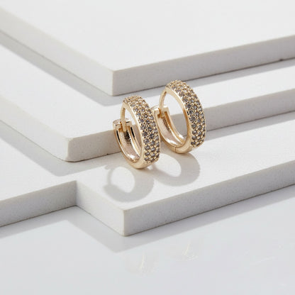 Gold hoop earrings with embedded stones on a white surface