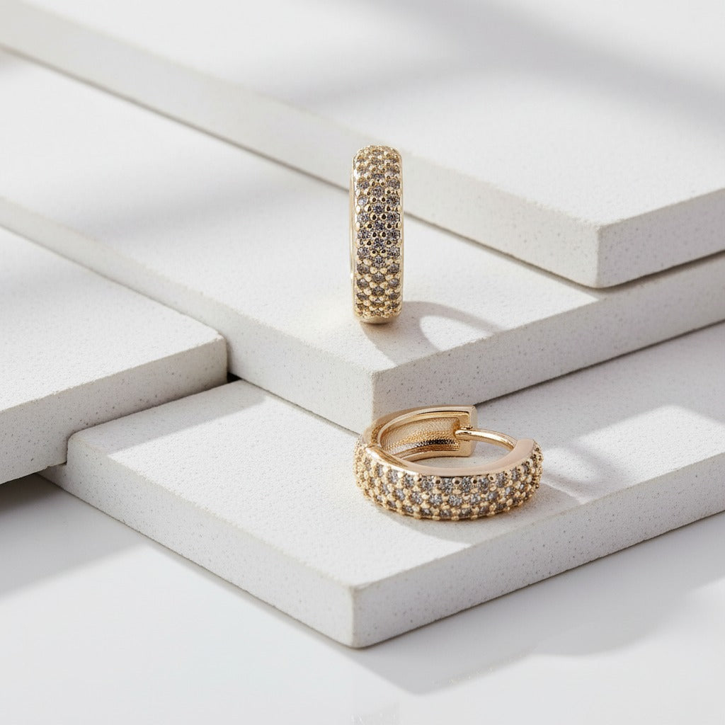 Gold hoop earrings on a light wooden surface