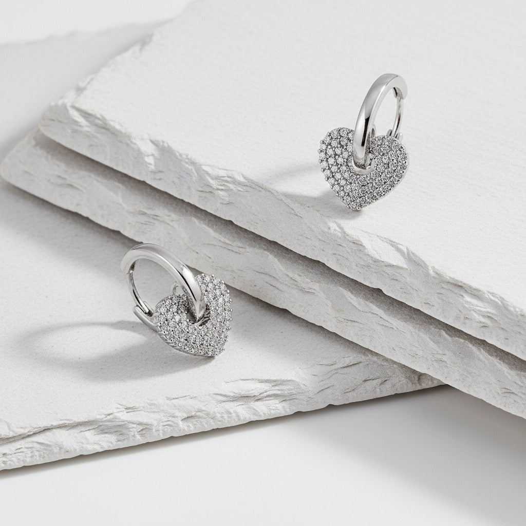 Heart-shaped silver earrings on a light wooden surface