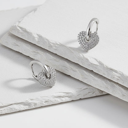 Heart-shaped silver earrings on a light wooden surface