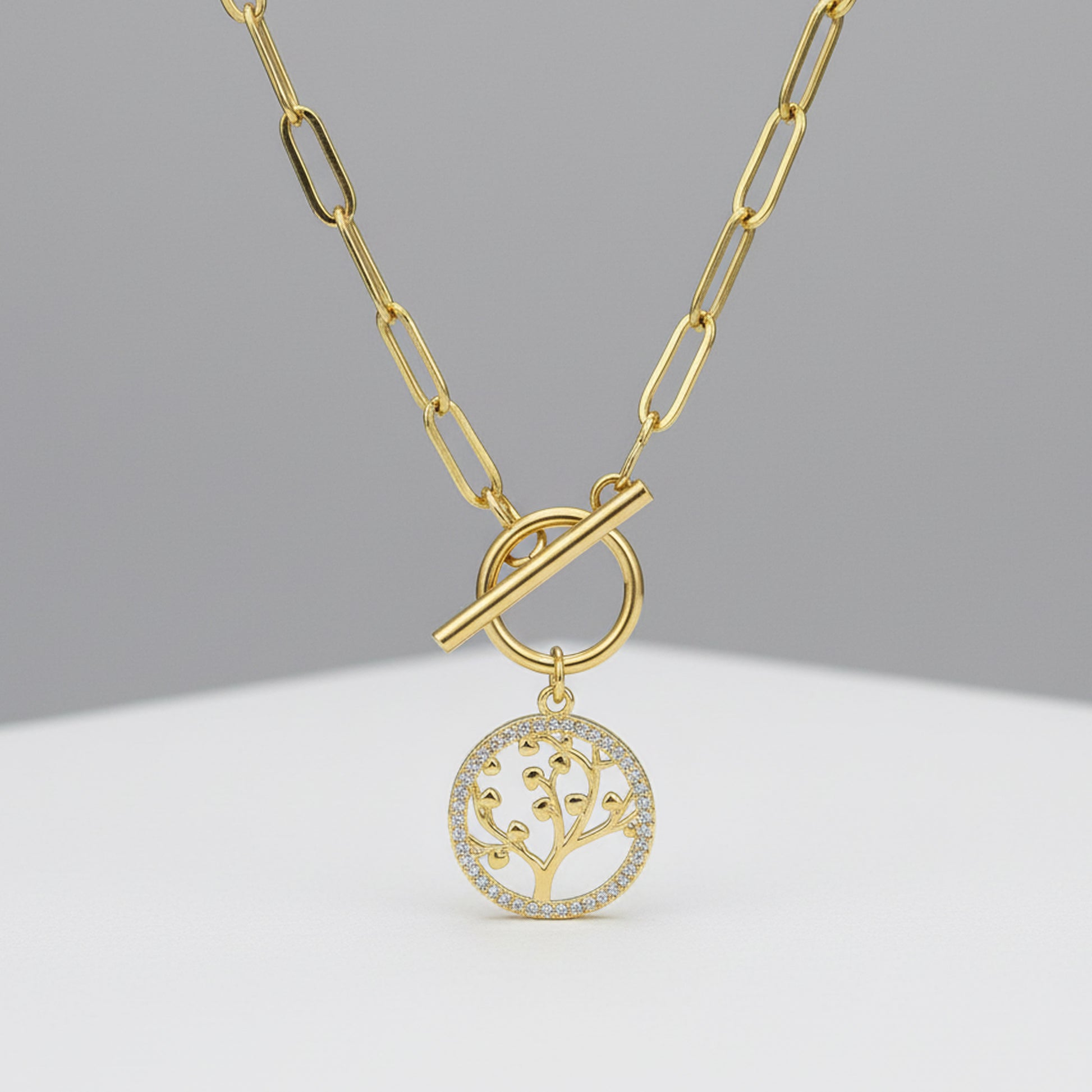 Gold necklace with the tree of life pendant on a gray background