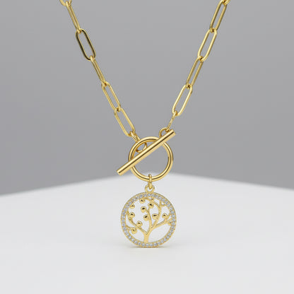 Gold necklace with the tree of life pendant on a gray background