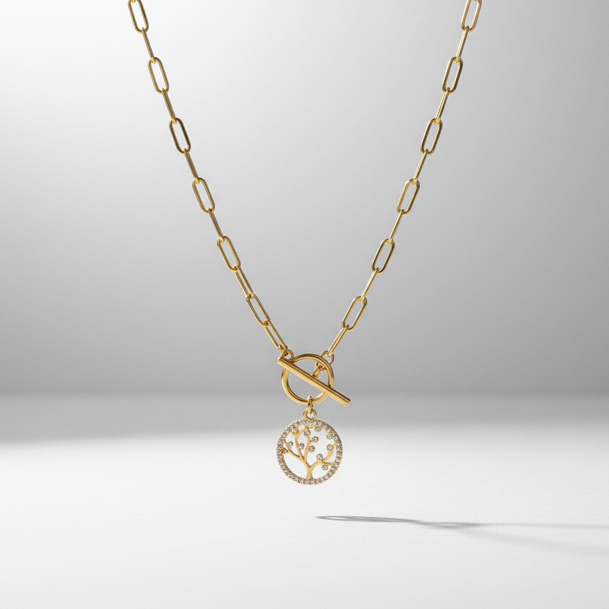 Gold necklace with a tree-of-life pendant on a light gray background
