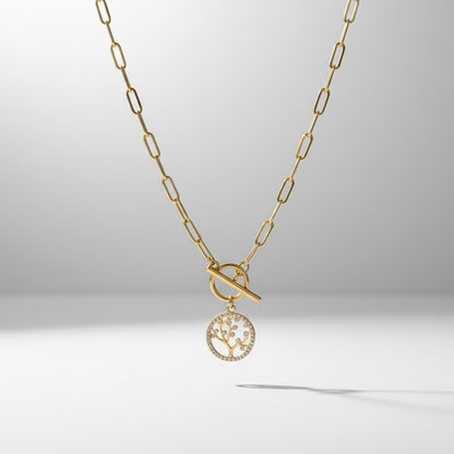 Gold necklace with a tree-of-life pendant on a light gray background